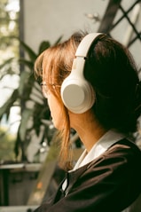 a woman wearing headphones sitting in front of a plant