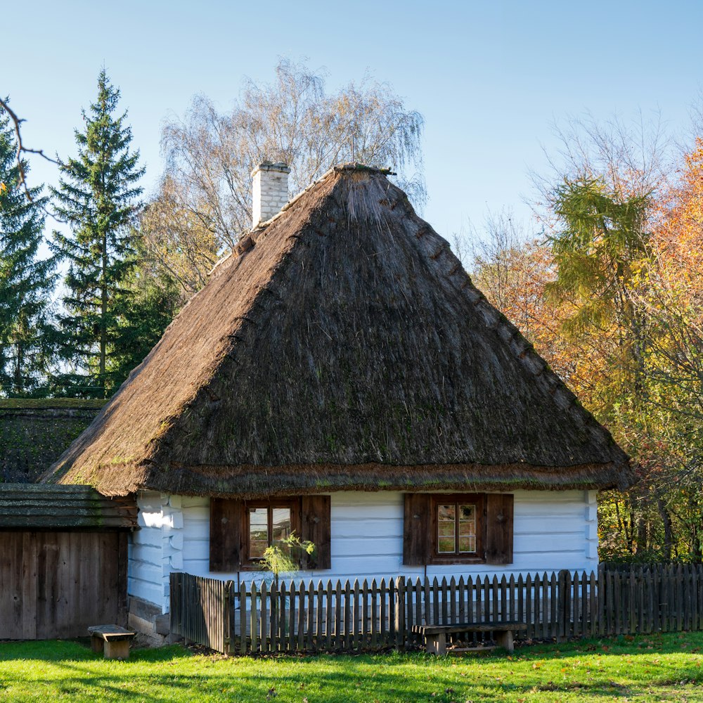 a white house with a thatched roof and a wooden fence