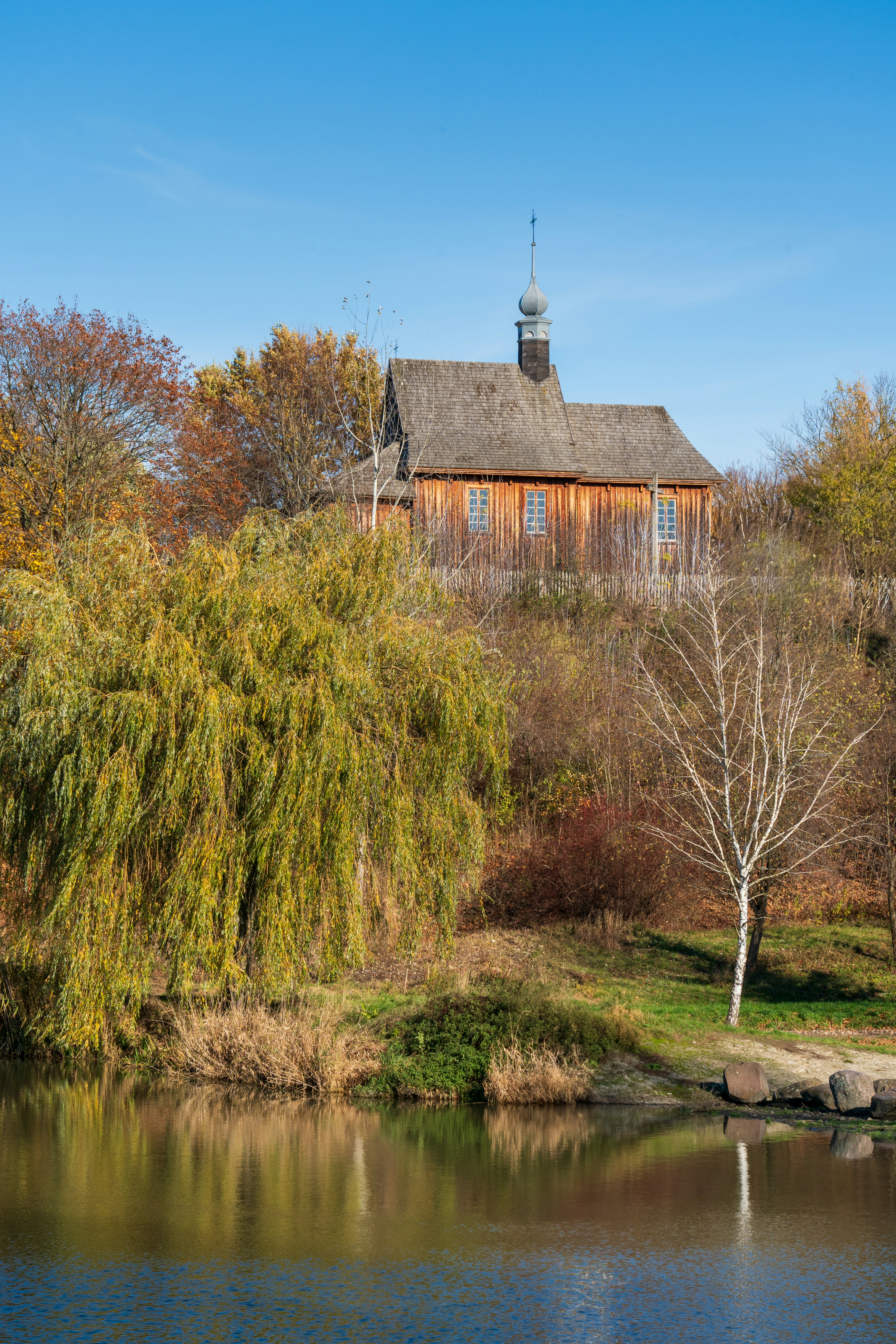 a house sitting on top of a hill next to a lake
