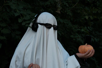 a person dressed in a ghost costume holding a pumpkin