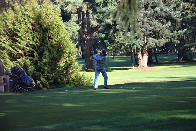 A golfer thoughtfully testing a driver on a sunny course, surrounded by lush green fairways.