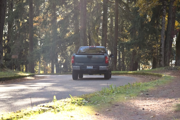 A rugged white pickup truck navigating a dirt road surrounded by trees