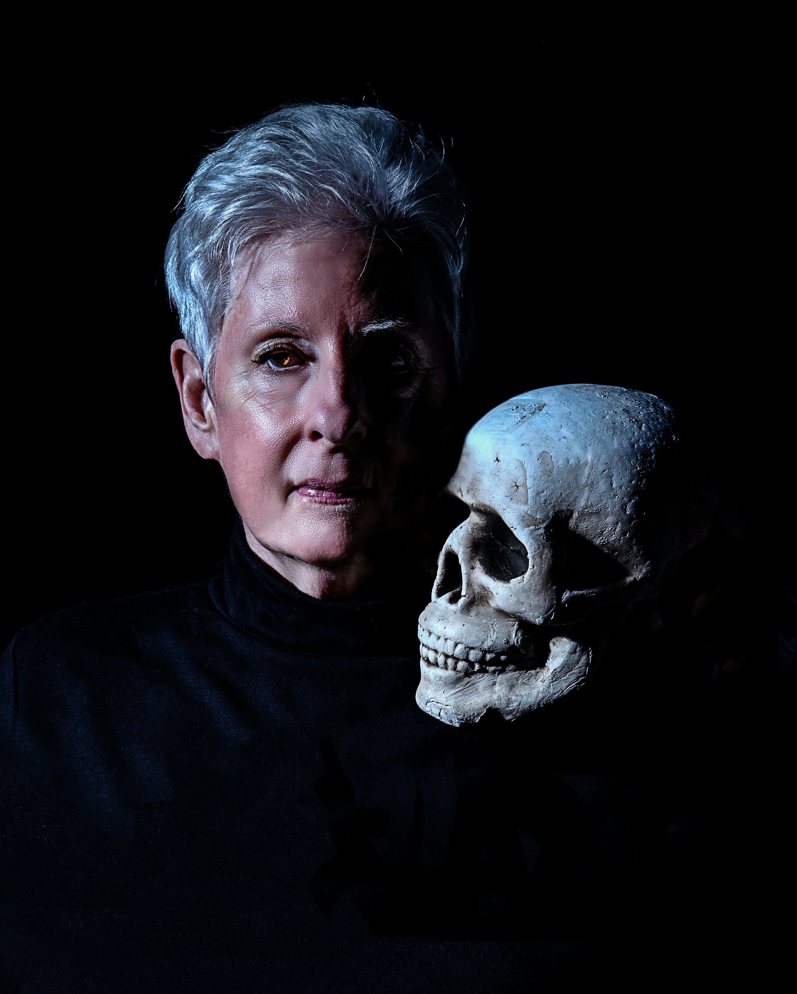 a woman holding a fake human skull in front of her face