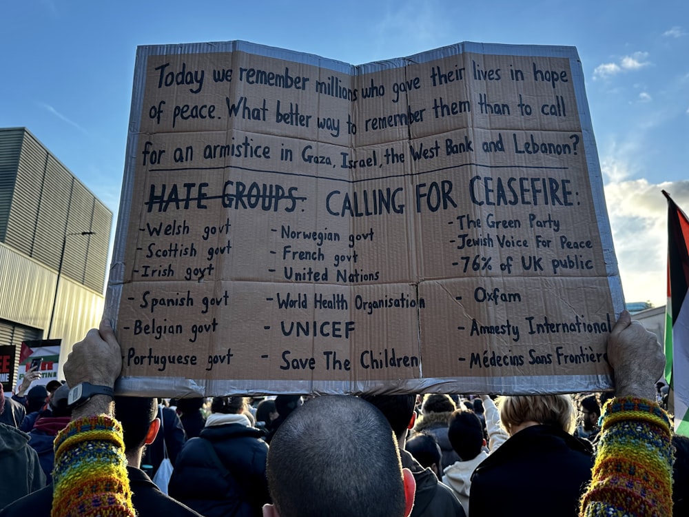 a person holding a cardboard sign in front of a crowd