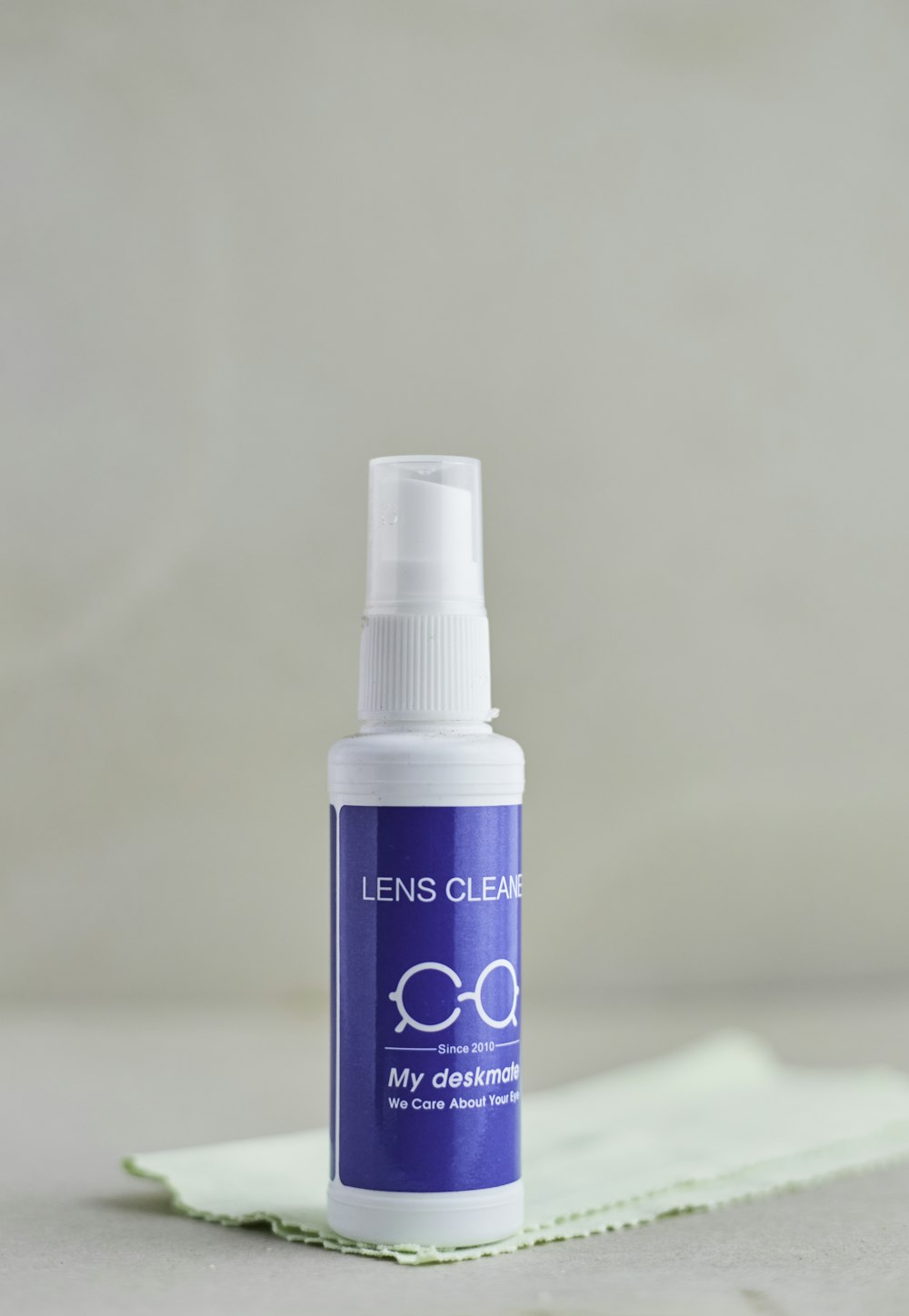 a bottle of lens cleaner sitting on top of a cloth