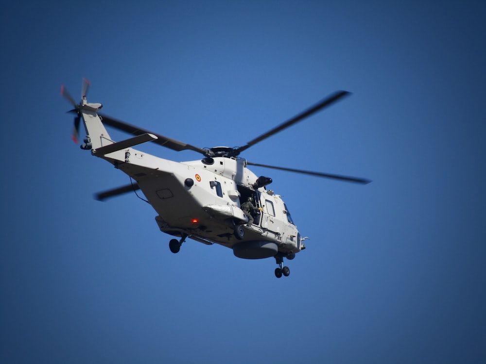 a white helicopter flying through a blue sky