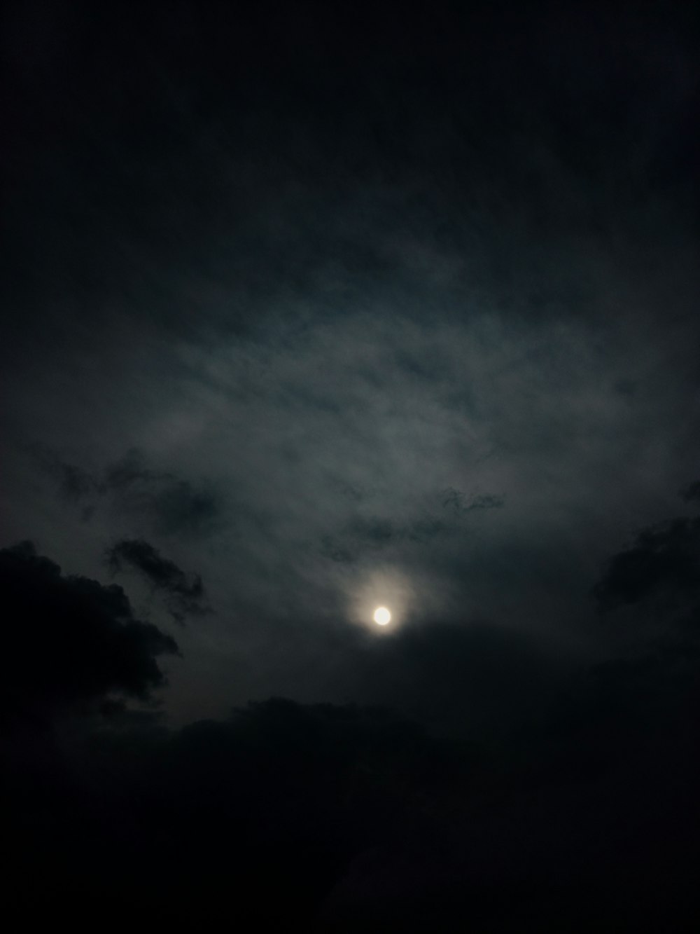 a full moon is seen through the clouds