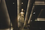 Dramatic black-and-white sculpture bathed in soft golden light against dark brown backdrop.
