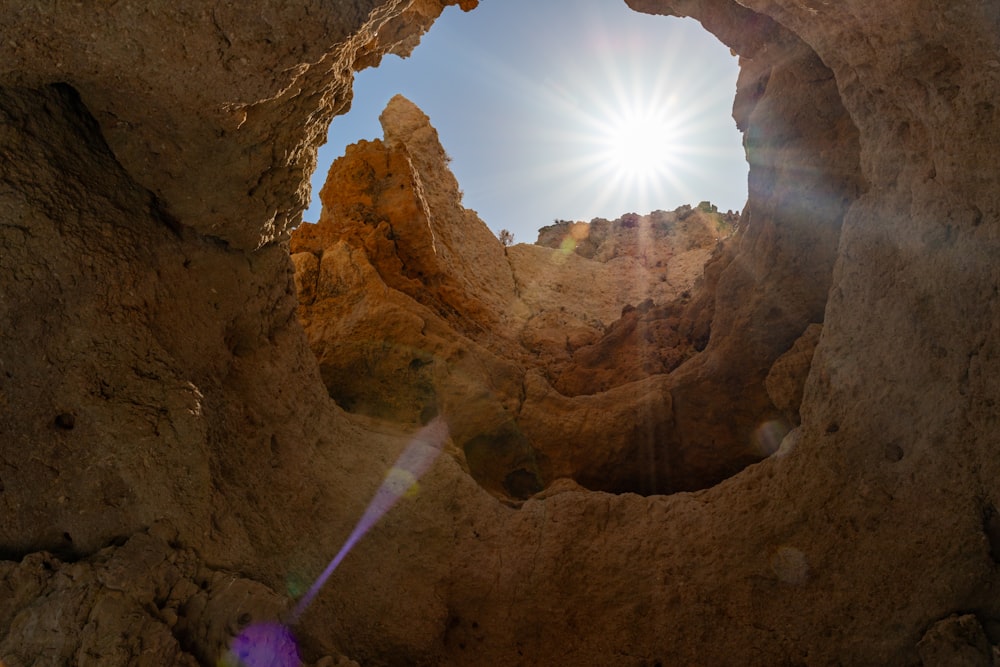 the sun shines through a hole in a rock formation