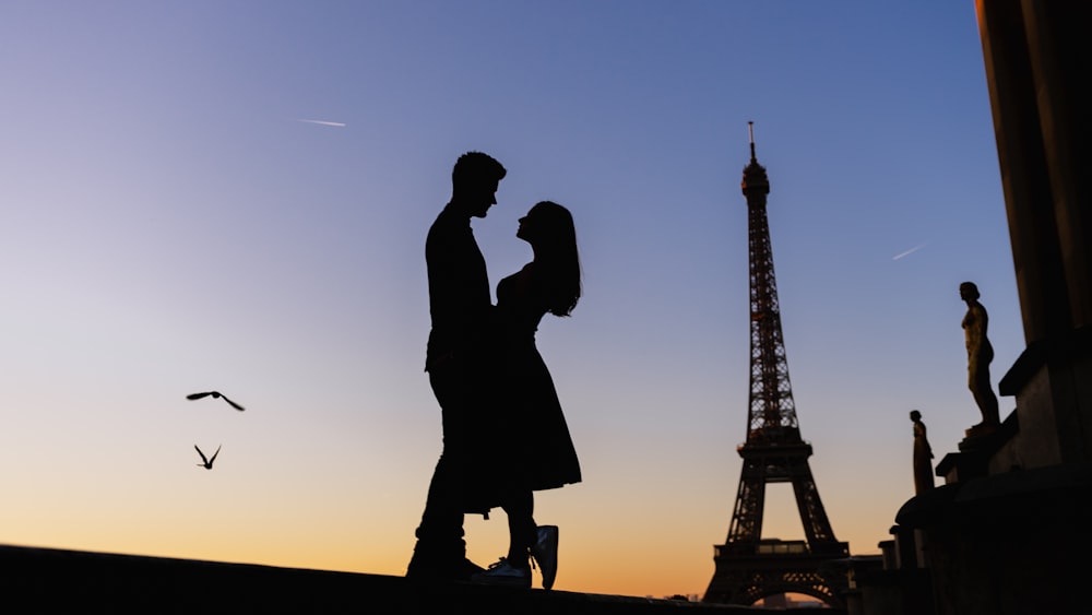 a man and a woman standing in front of the eiffel tower