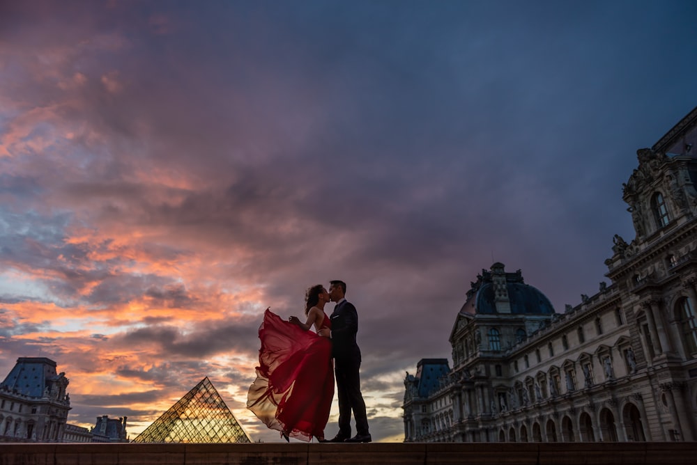 a man and a woman kissing in front of a pyramid