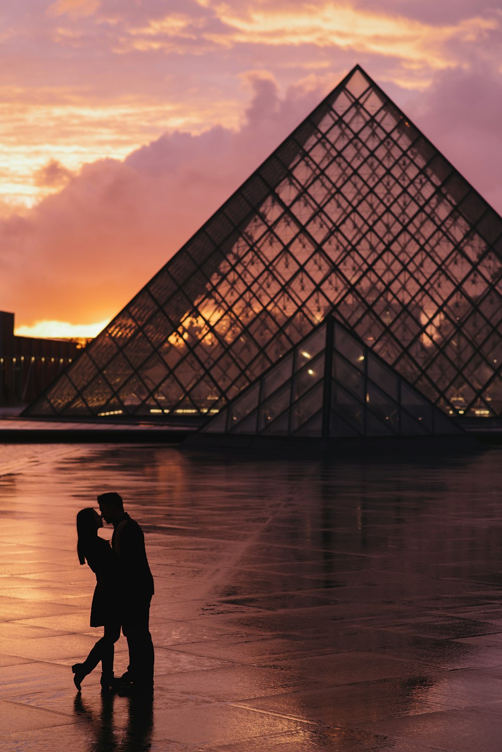 a couple kissing in front of a pyramid