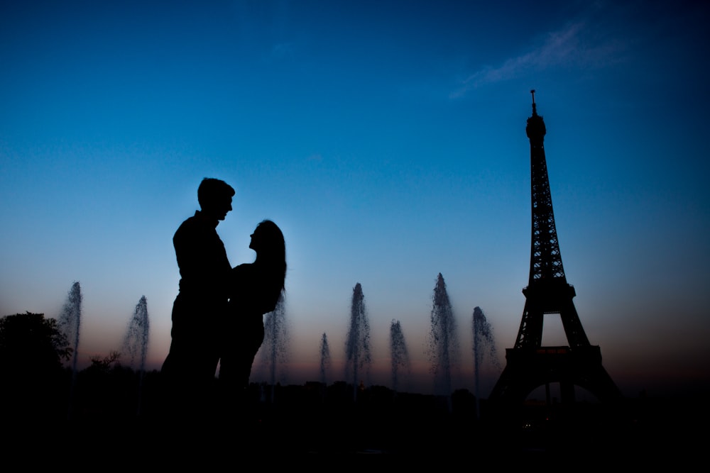 a silhouette of a couple standing in front of the eiffel tower