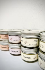 Luxurious jar of creamy body butter surrounded by fresh berries and natural leaves.