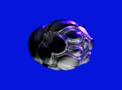 A cluster of transparent, reflective bubbles with a glass-like texture is set against a bright blue background, with light purple highlights providing depth and contrast.