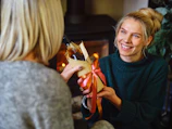 Smiling women delivering gifts to a local nonprofit center decorated for the holidays.