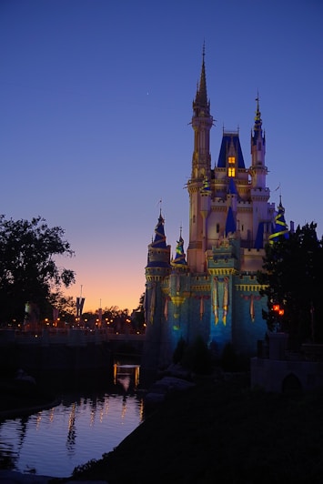 a castle lit up at night next to a body of water