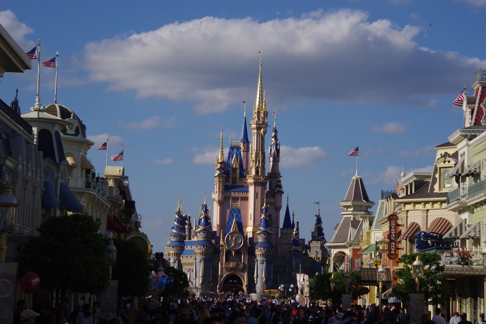 a crowd of people walking down a street in front of a castle