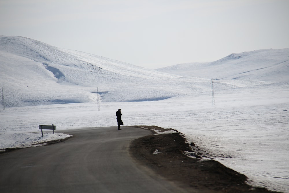 a person standing on the side of a snow covered road