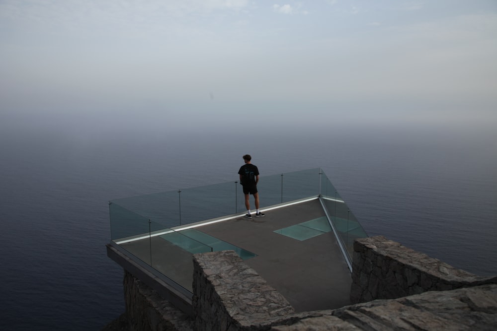 a man standing on top of a cliff next to the ocean