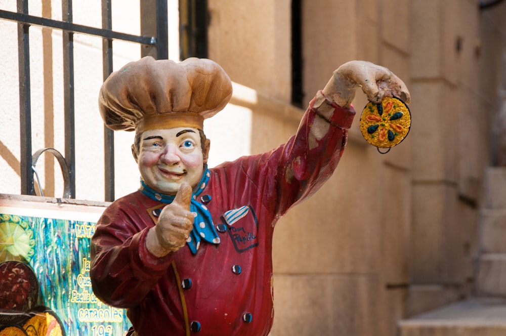 a statue of a chef holding a pizza