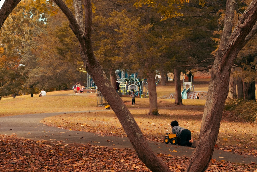 a couple of people sitting on top of a leaf covered ground