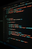 A close-up view of a computer screen displaying HTML and CSS code for a login form. The code includes elements like head, body, various input fields for username and password, and linked style sheets. The text is primarily in blue, white, orange, and green, set against a dark background.