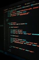 A close-up view of a computer screen displaying HTML and CSS code for a login form. The code includes elements like head, body, various input fields for username and password, and linked style sheets. The text is primarily in blue, white, orange, and green, set against a dark background.