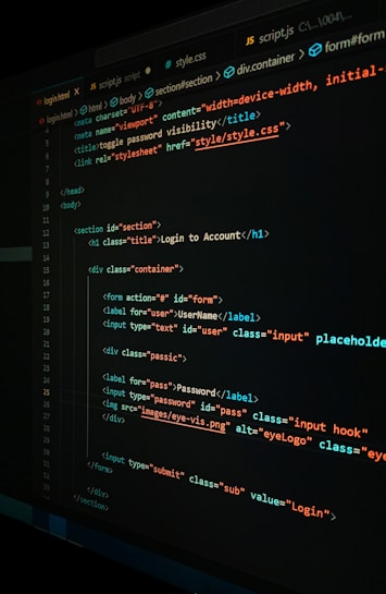 A close-up view of a computer screen displaying HTML and CSS code for a login form. The code includes elements like head, body, various input fields for username and password, and linked style sheets. The text is primarily in blue, white, orange, and green, set against a dark background.
