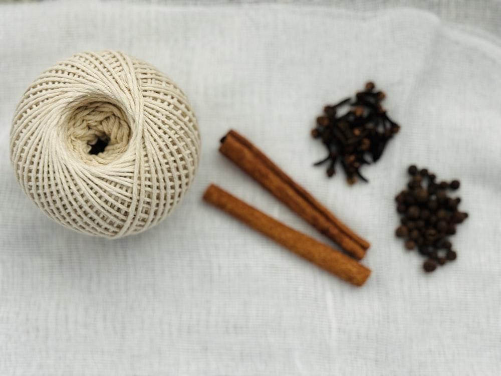 a ball of twine, cinnamon sticks, and cloves on a white