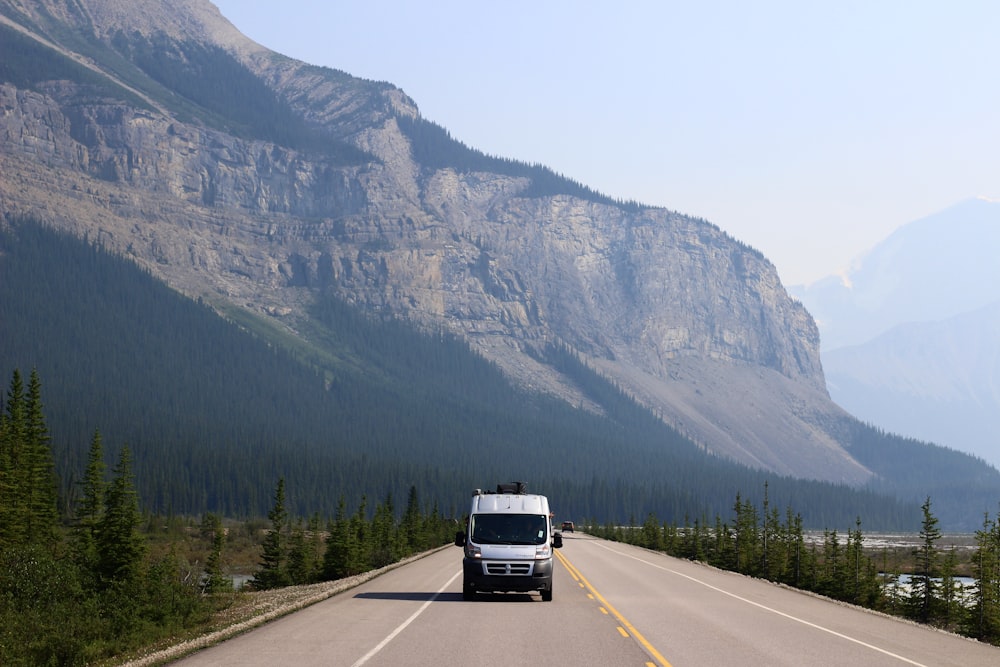 a van driving down a road in front of a mountain