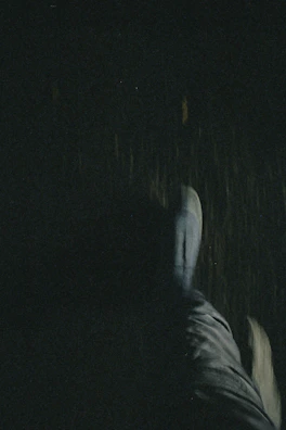 A dramatic shot of stiletto heels stepping onto a dark floor, with shadows playing around.