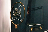 A vintage microphone set against a deep charcoal backdrop, ready for recital.