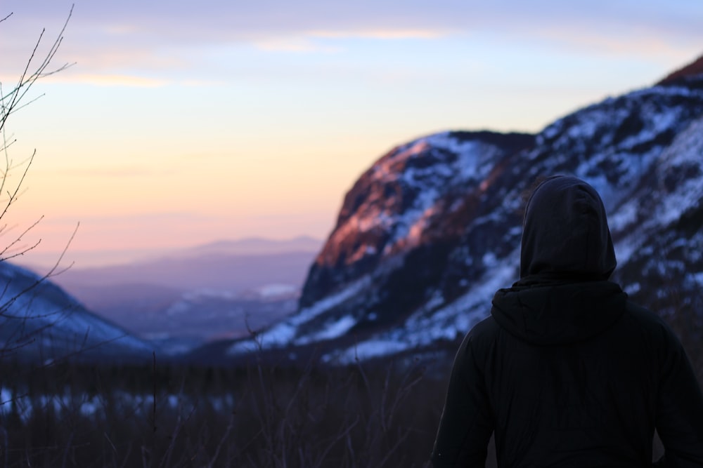 a person standing in front of a mountain at sunset