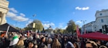 A diverse group of people gathered outdoors, discussing community plans under a bright sky.