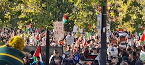 An outdoor political rally with people holding signs and banners.