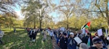 A group of diverse community members planting trees together in a sunny park.