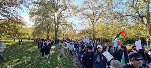 A group of diverse community members planting trees together in a sunny park.