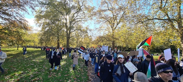 A group of diverse community members planting trees together in a sunny park.