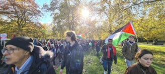 A diverse group of volunteers planting trees in a sunny park.