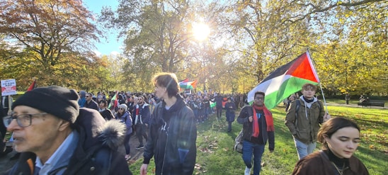 A diverse group of volunteers planting trees in a sunny park.