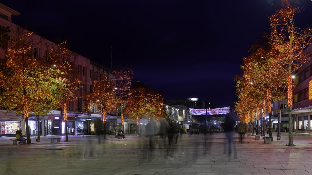 a group of people walking down a street at night