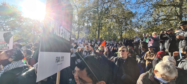 Supporters gathering together holding signs that read 'For the People' in a sunny California park.
