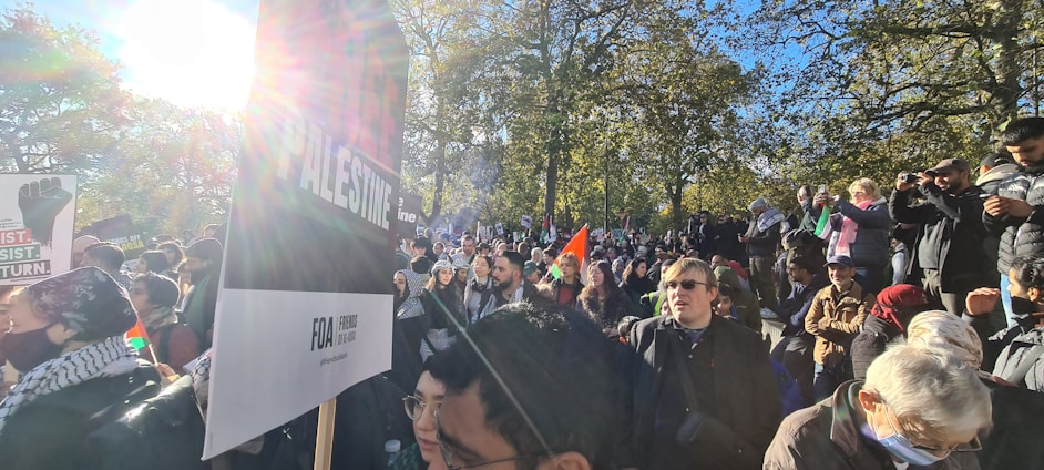 A diverse group of community members smiling and holding hands in a sunny park.