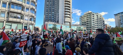 A vibrant crowd gathered outside Independence Hall in Philadelphia, waving CDC-USA flags under a clear blue sky.