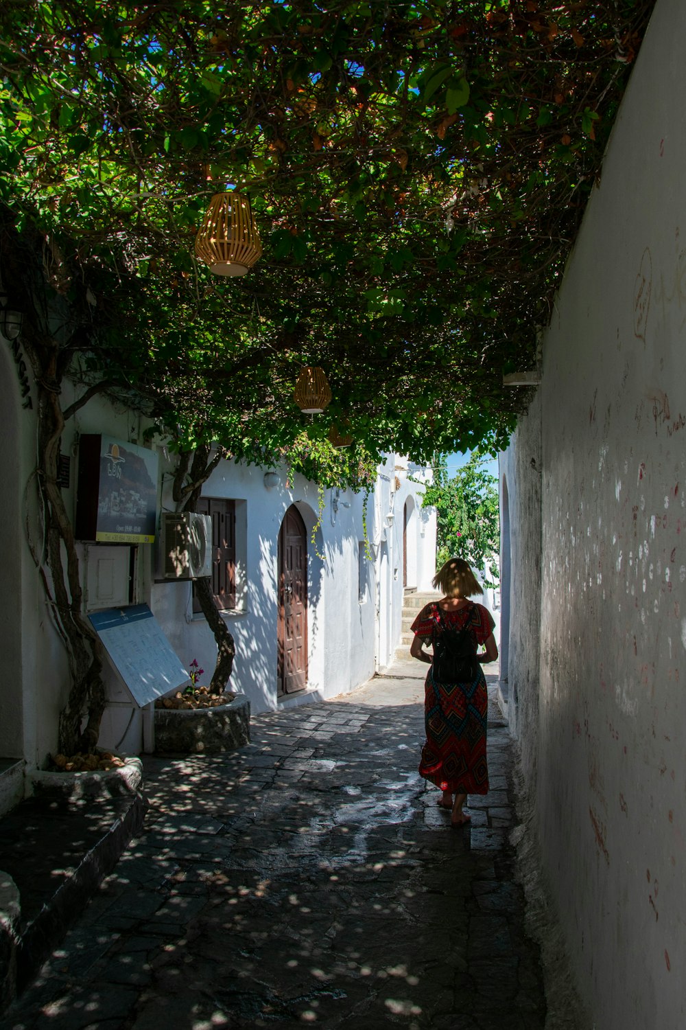 a woman is walking down a narrow alley way