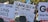 A collection of protest signs is held up in a crowd. Messages on the signs include demands for ceasefire, criticisms of political leaders, and calls to stop war crimes. The background includes trees and more protest signs, some with political and peace-related messages.