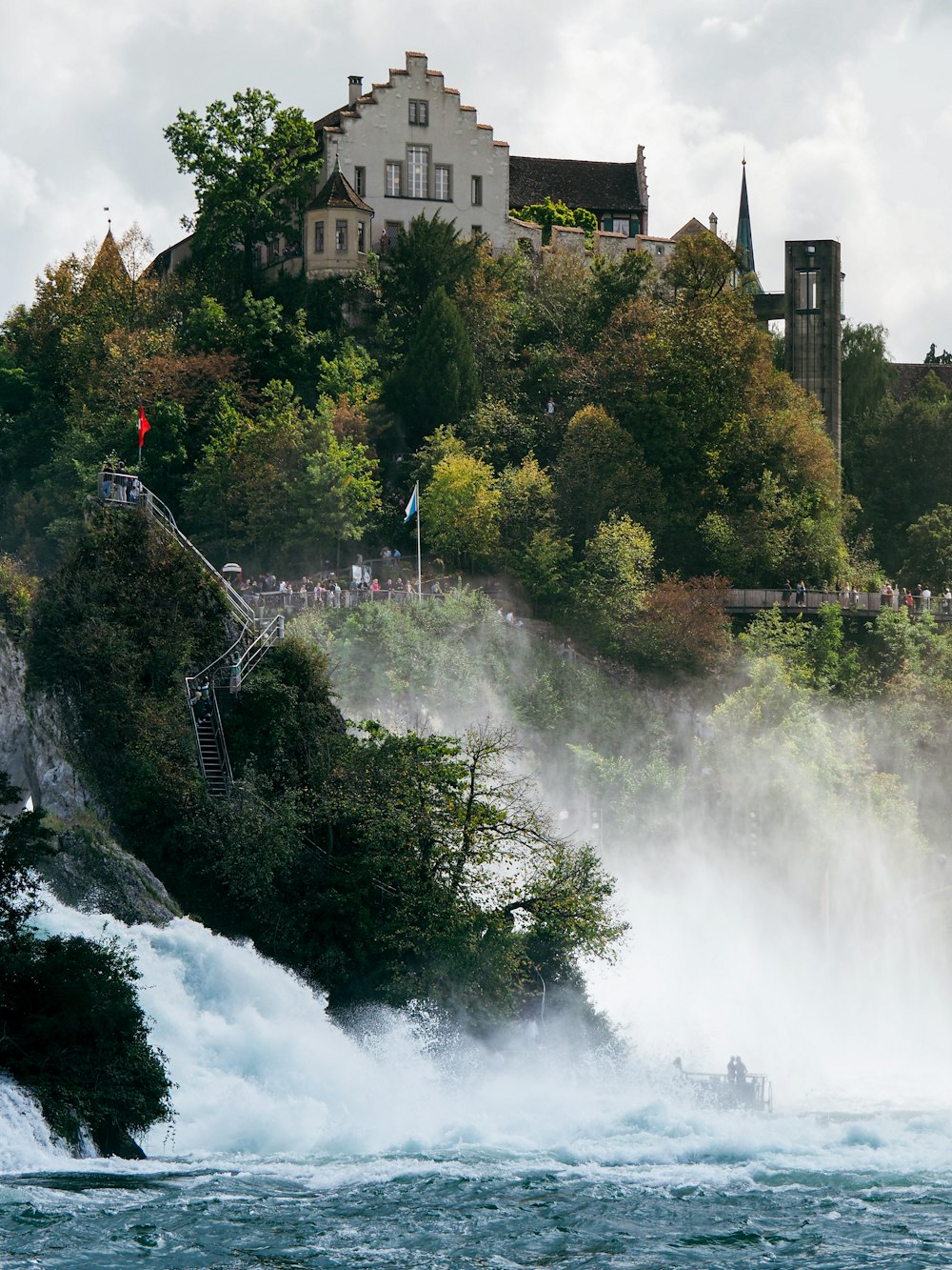 a large waterfall with people standing on the side of it