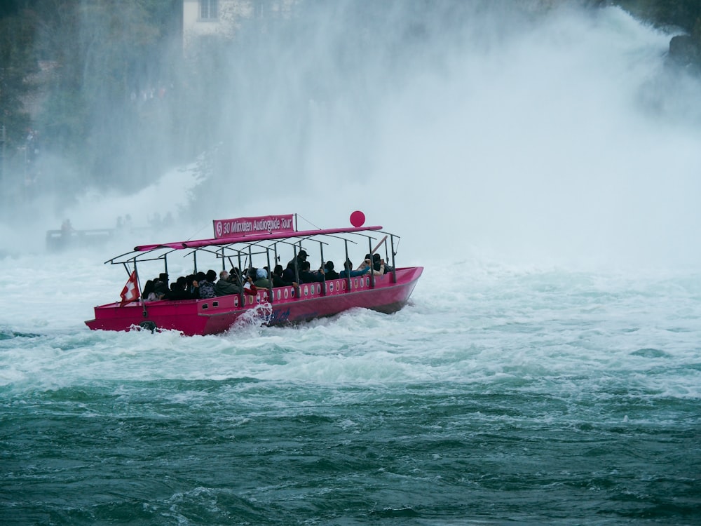 un barco rosa lleno de gente en el agua