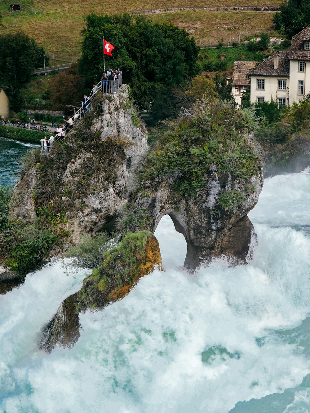 a group of people standing on top of a cliff next to a body of water